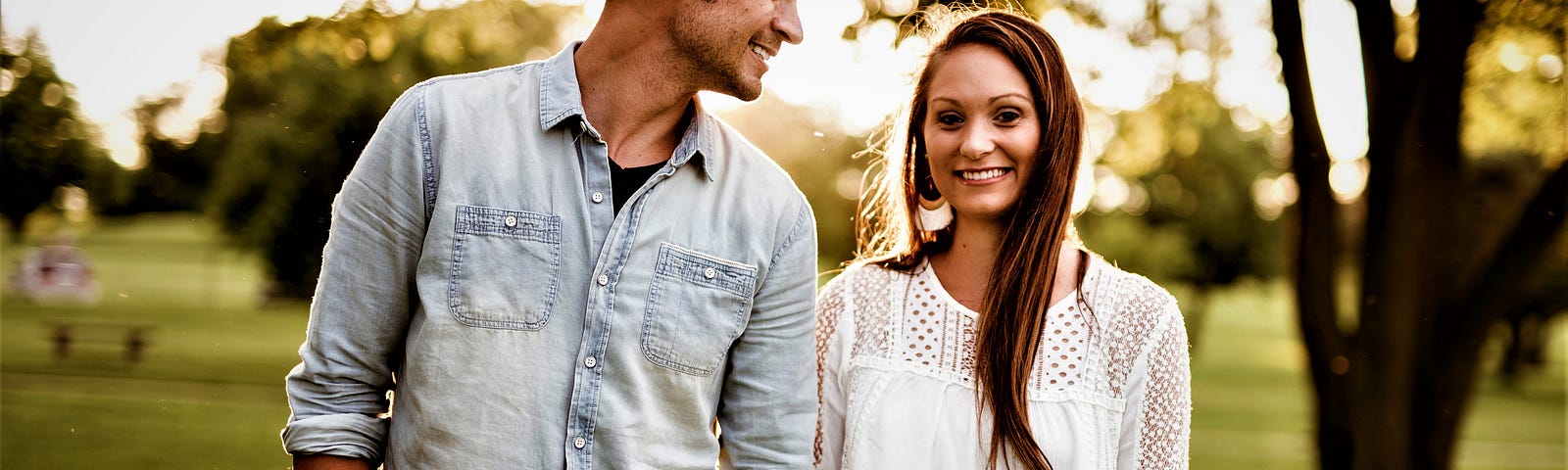 happy young couple standing in park holding hands