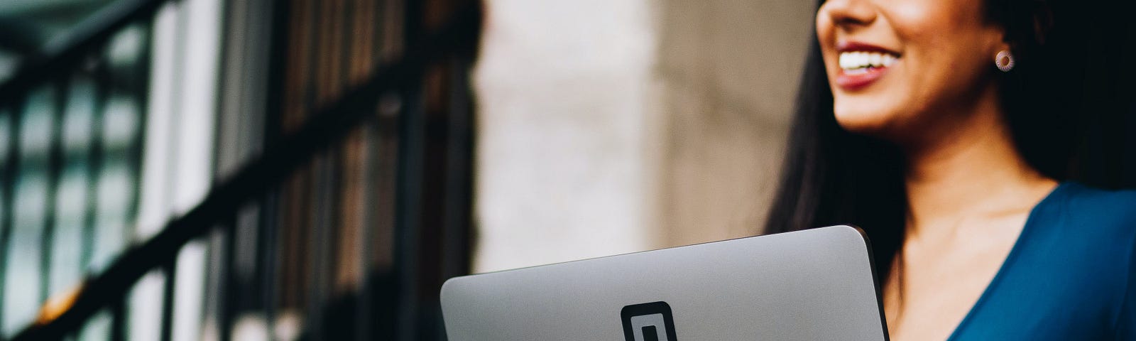 A lady smiling behind a laptop