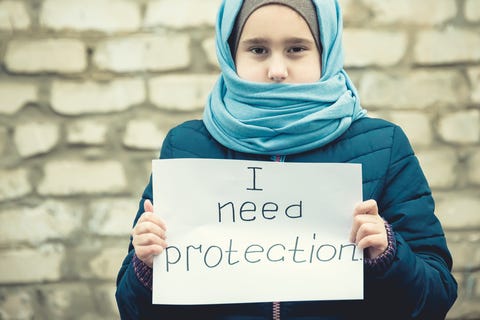 Refugee girl holding a placard asking for protection