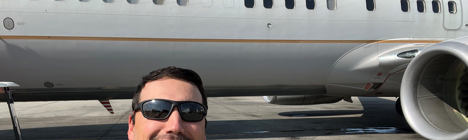 Alex posing with United aircraft on the runway.