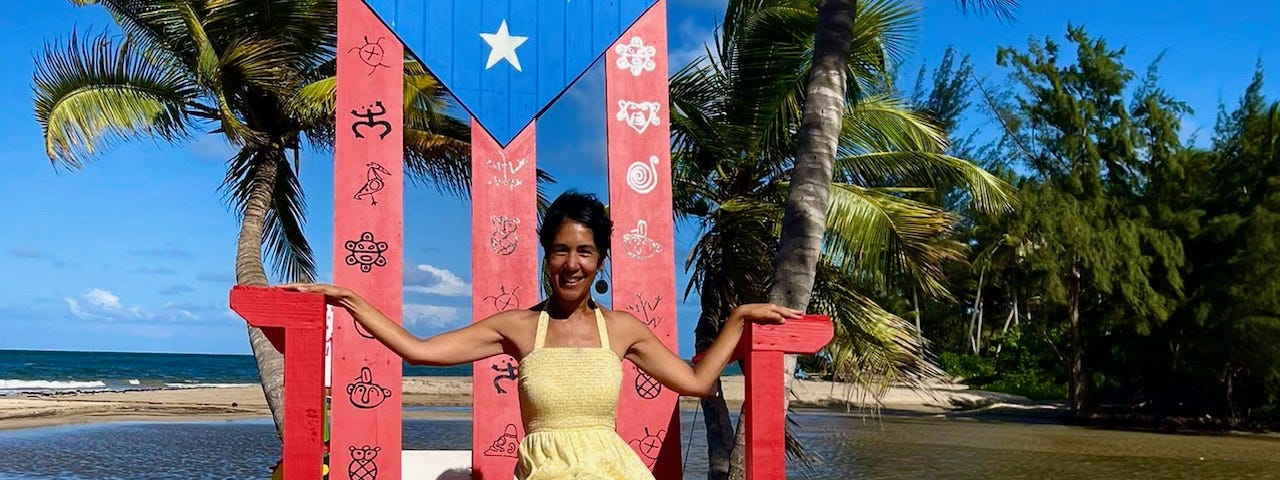 Loíza, Borikén, Puerto Rican flag chair, beach, yellow dress, barefoot, the beach, Brown woman smiling