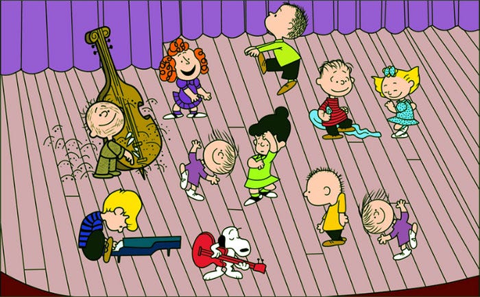 Still image from “A Charlie Brown Christmas” showing “Peanuts” characters playing piano, guitar, and stand-up bass, and dancing on a stage before rehearsal for their Christmas pageant