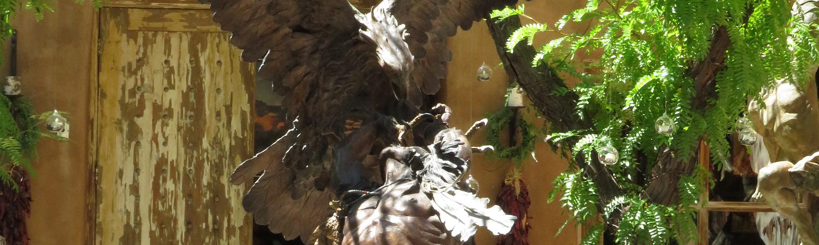 A lifesize bronze sculputure of a giant eagle attacking a muscular Native American Indian as he reels back in apparant pain, by artist Vic Payne in Santa Fe New Mexico