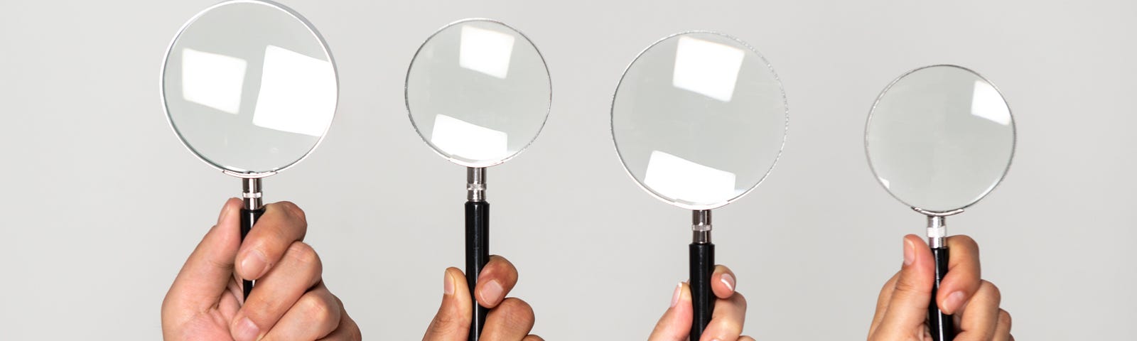 Four hands holding magnifying glasses. Photo by solidcolours/Getty Images