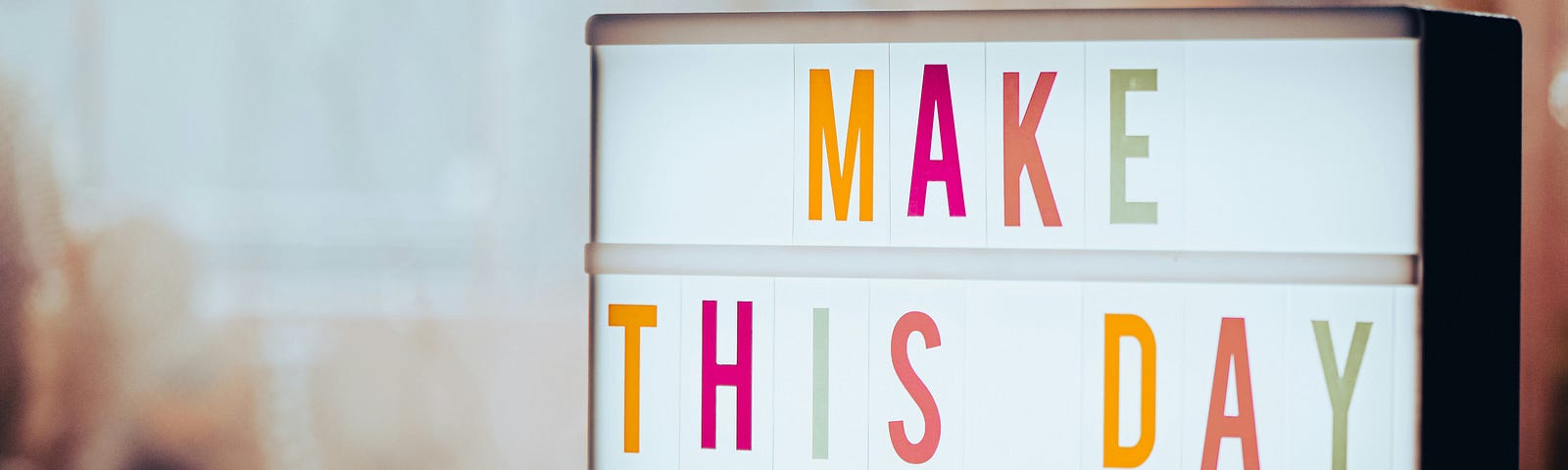 A light box that says make this day great in bright colours.