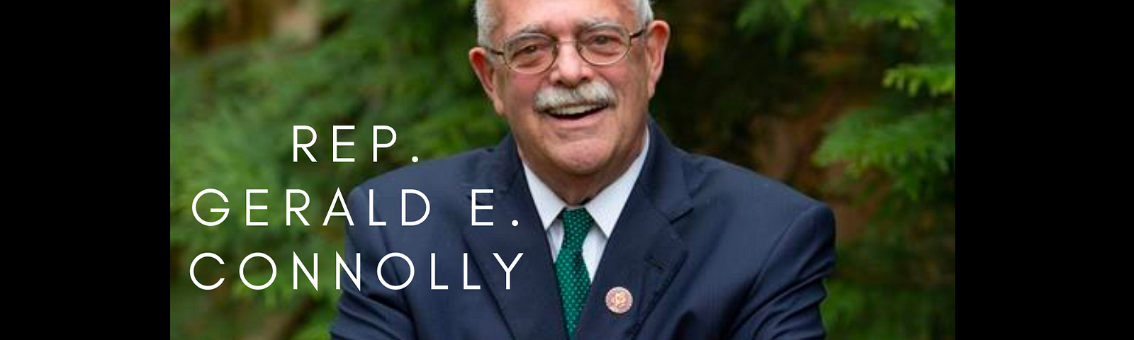 Image of Rep. Gerald E. Connolly standing with arms crossed in front of greenery.