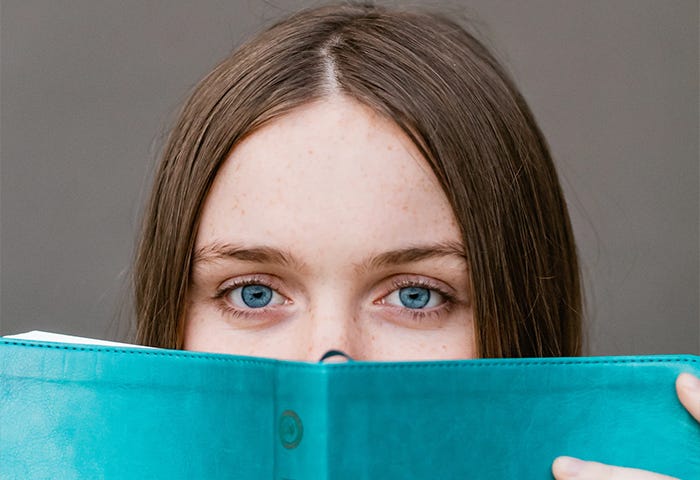 woman covering her face with teal book