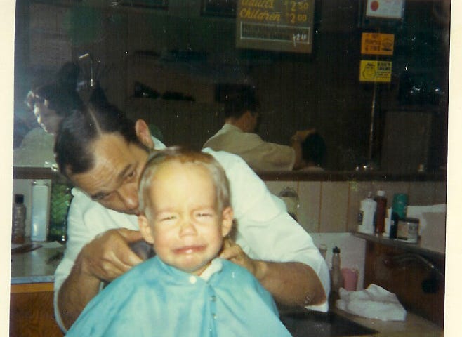 A baby is barbers chair crying.