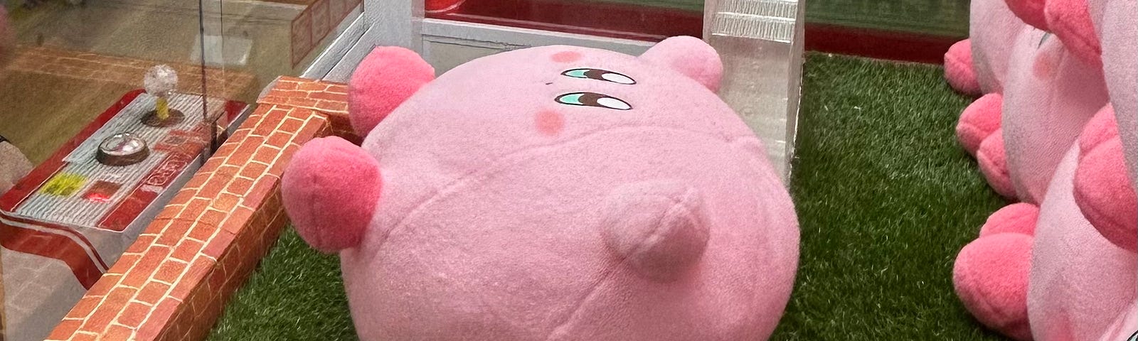 Adorable giant soft toy Kirby begging for release from a claw machine