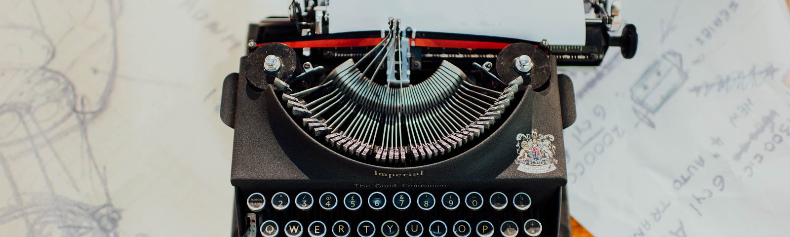 A black typewriter with sheets of paper around it on a desk.