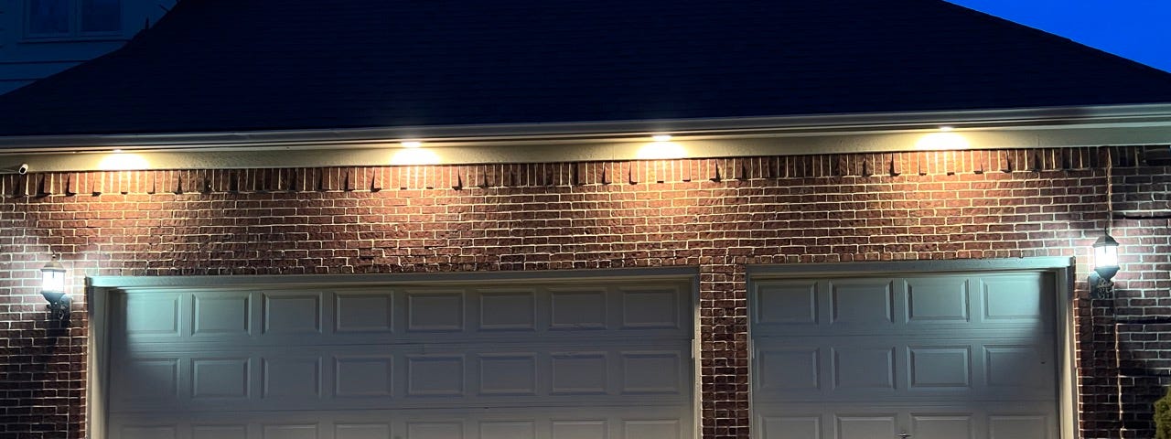 A well-lit three car garage pictured from the outside.