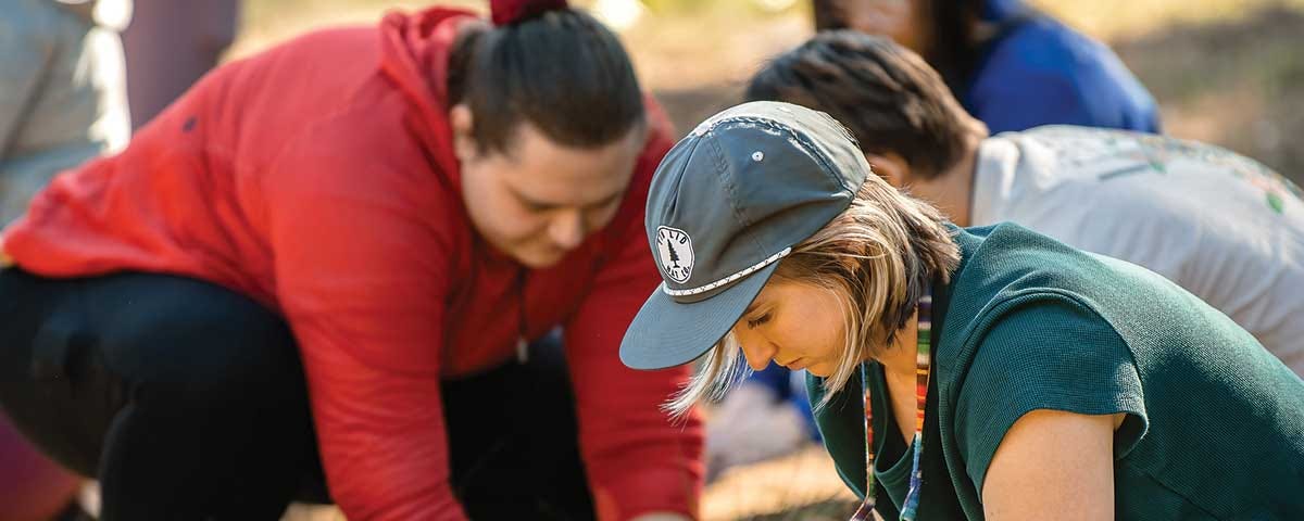 Students and faculty members dig into a patch of land and prepare to place plants native to Colorado