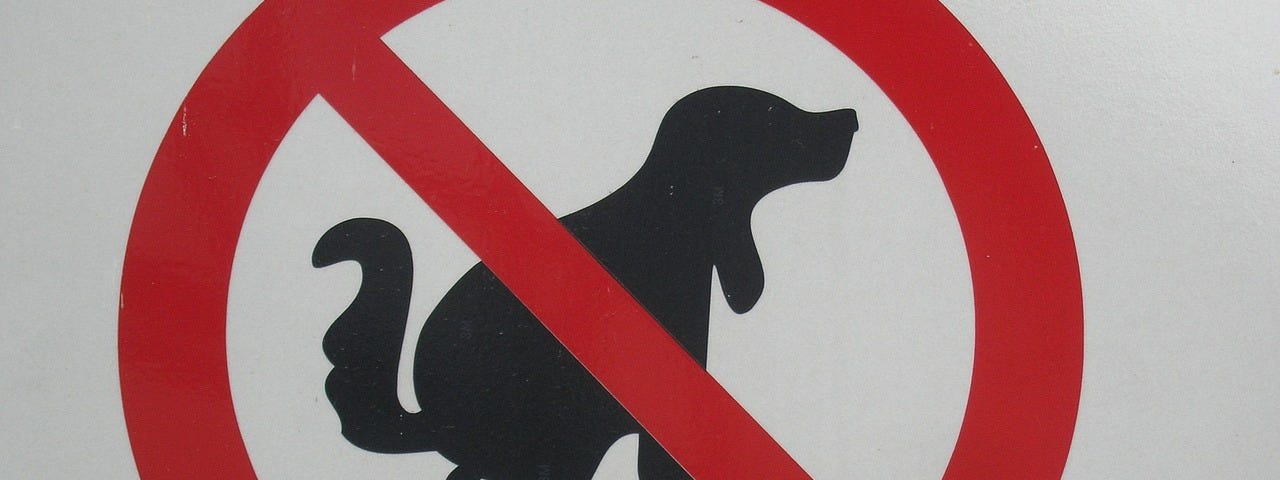 A red warning sign banning dog defecation.