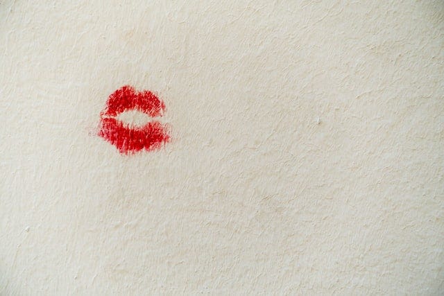 a white wall with an imprint of a red lip stick kiss.