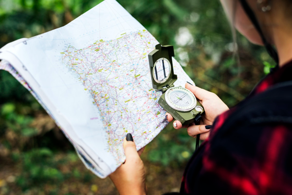 A hiker in the woods, using a map and compass to figure out location