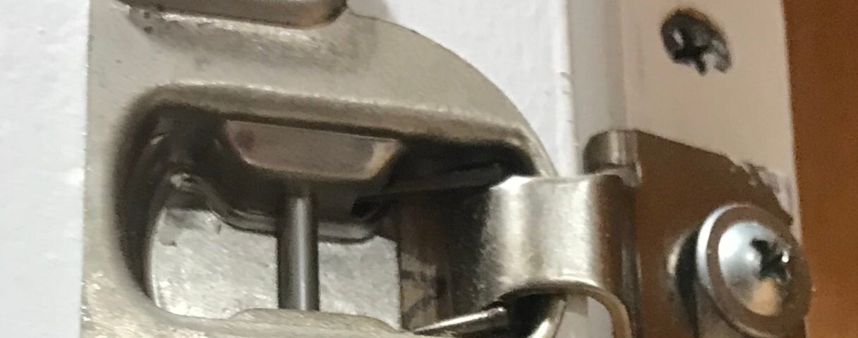 A close-up of a kitchen cabinet hinge.