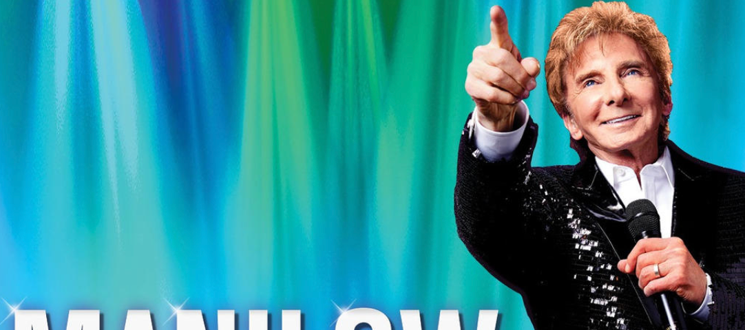 photo of singer Barry Manilow pointing at the audience. Text reads Manilow.