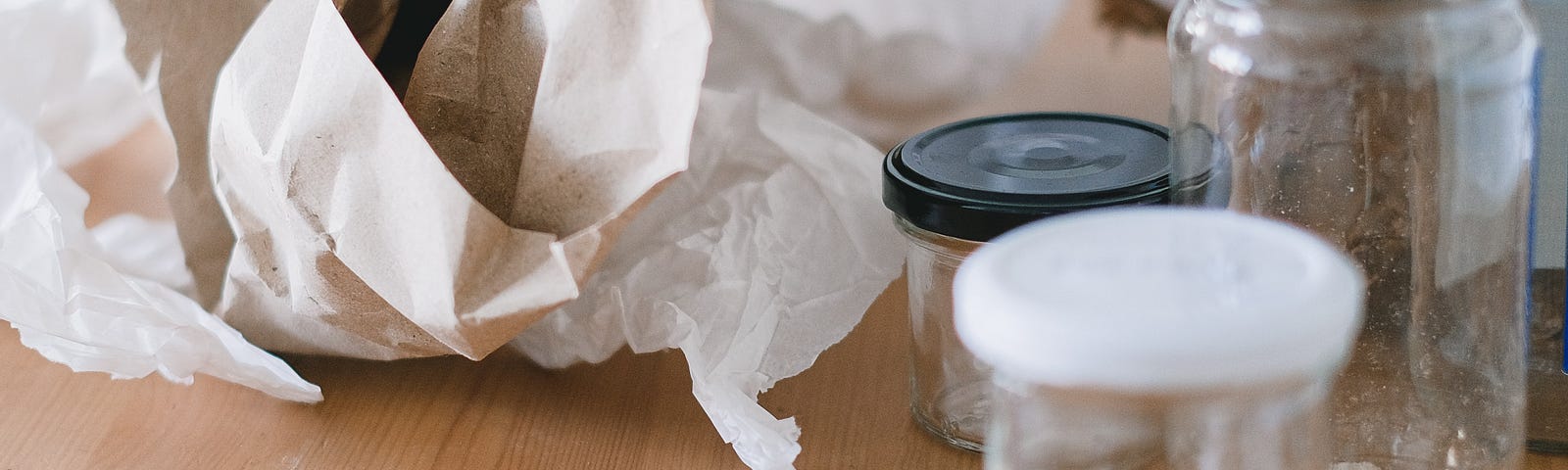 Glass jars and crumpled paper on wooden table