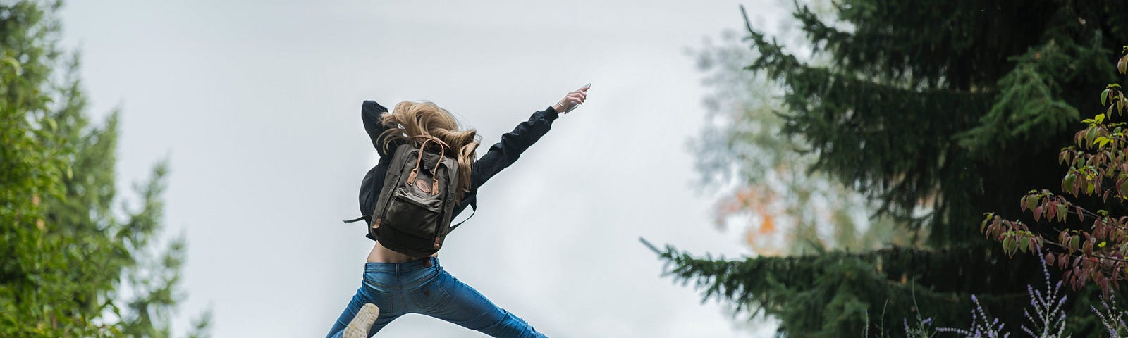 A girl with a backpack with visible joy, jumping into the unknown.