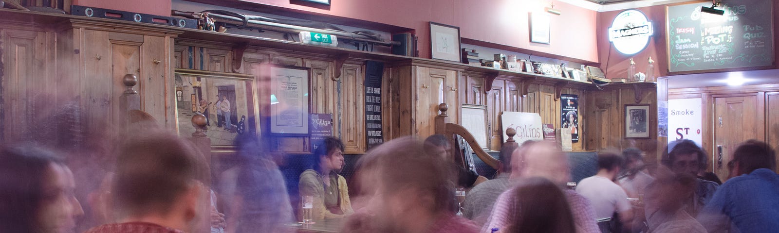 A slightly blurred picture showing a crowd of people seated in a pub.