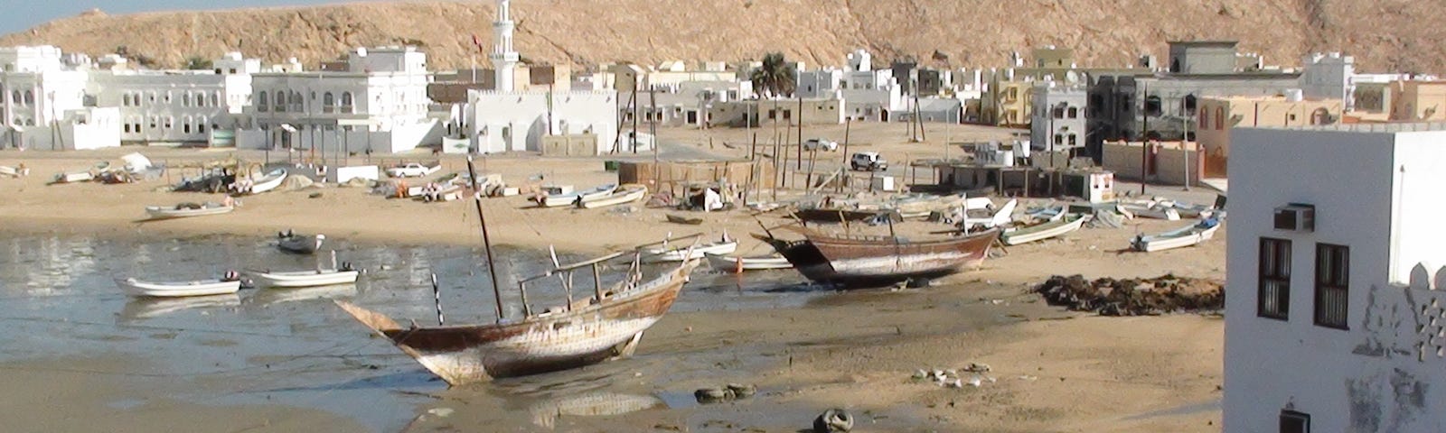 Port of Sur, an Omani city on the coast of the Gulf of Oman. The picture shows dhows and white houses around the port.