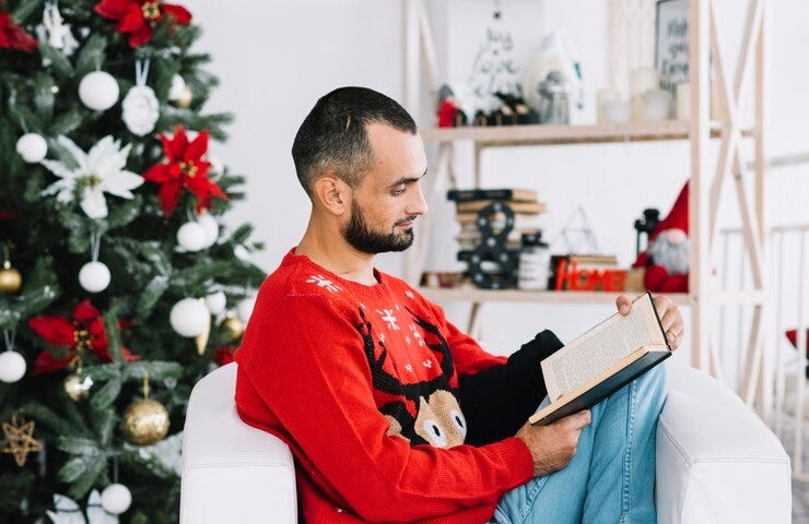 Man reading book by Christmas tree