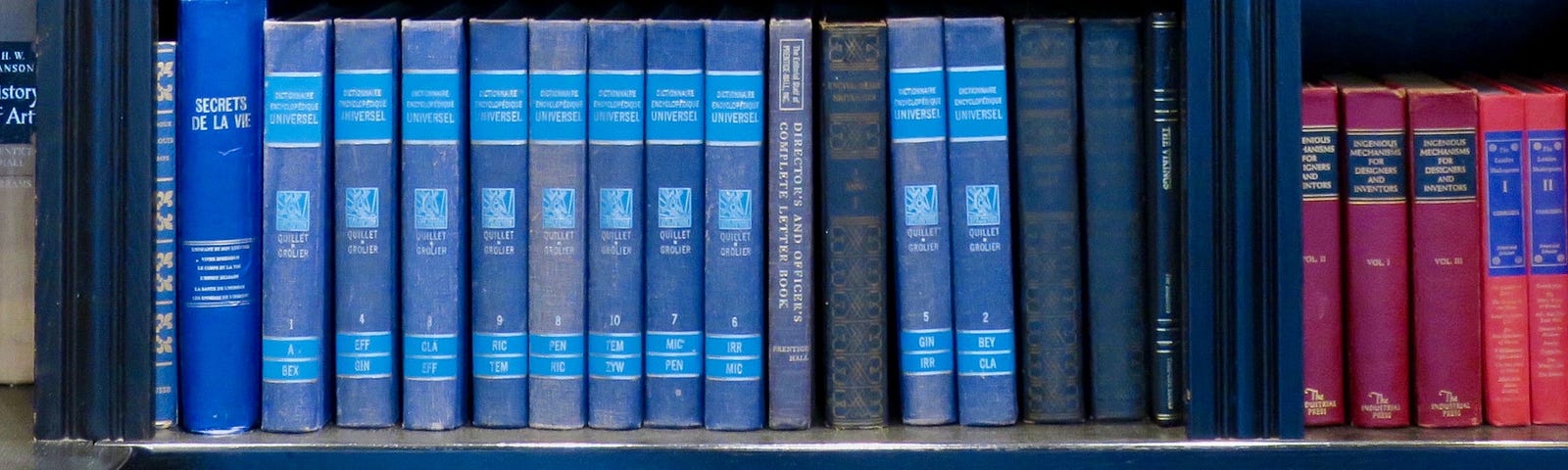 Row of older books, with covers in Blue, Red and Pink.