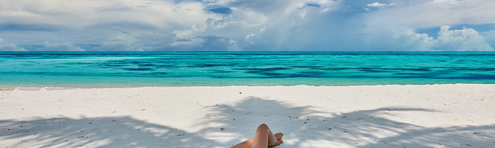 Woman in bikini at tropical beach under the palm tree