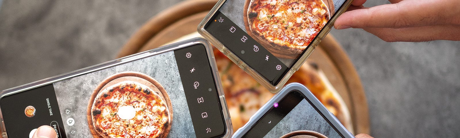 people holding smartphones taking picture of pizza