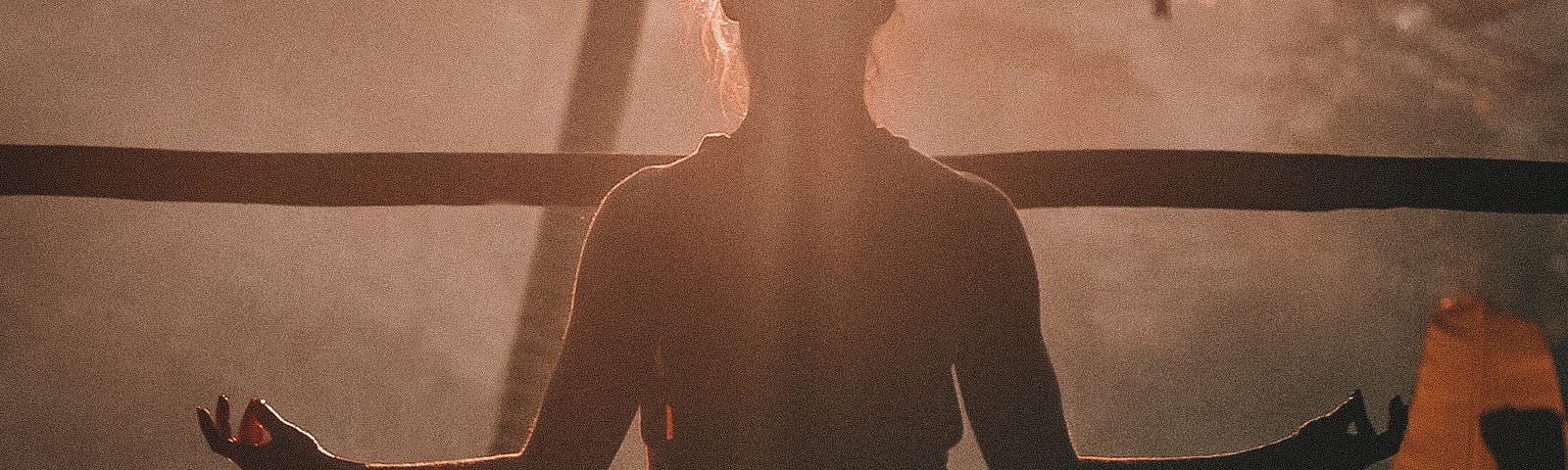 Person sitting in yoga position, in silhouette.