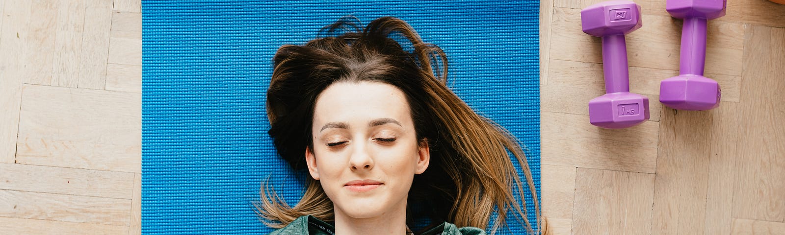 Girl lying on a yoga mat with closed eyes.