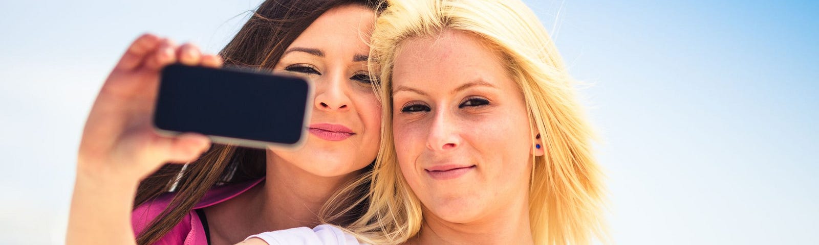 A lesbian couple taking a selfie outdoors