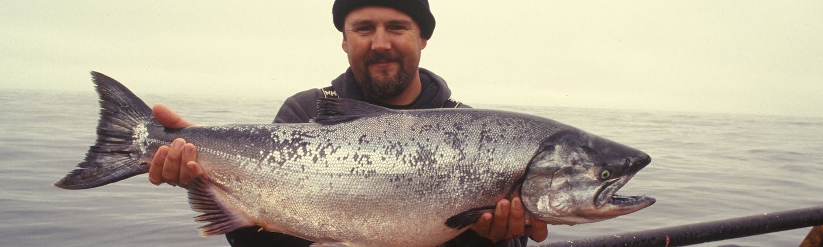 Photo of fisherman holding big salmon. Fishing. Ocean. Sports. Humor. Funny. Weird.