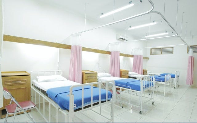 a hospital room with white walls, blue beds and pink curtains