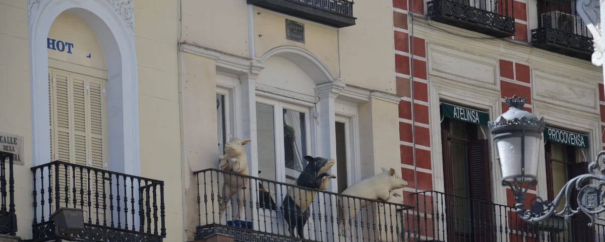 Three pigs on a Spanish townhouse balcony.