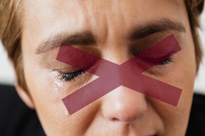 Close up of a woman crying with a red X over her face