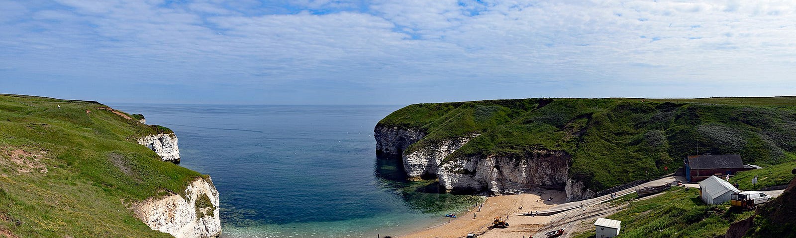 View of North Landing, Flamborough, Yorkshire, UK — chalk headlands either side with sandy bay on a sunny day.