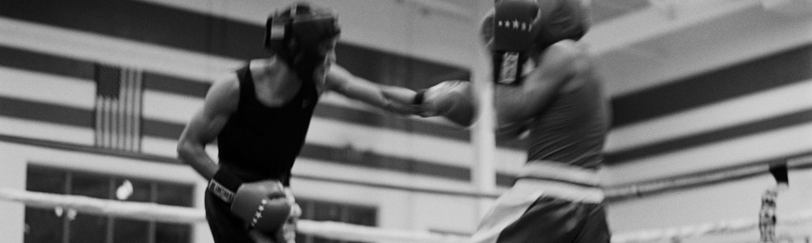 Black and white photo of two men boxing in an indoor ring