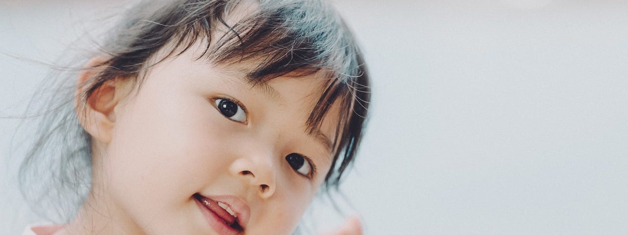 Photo of a young girl holding her hands out looking quizzical