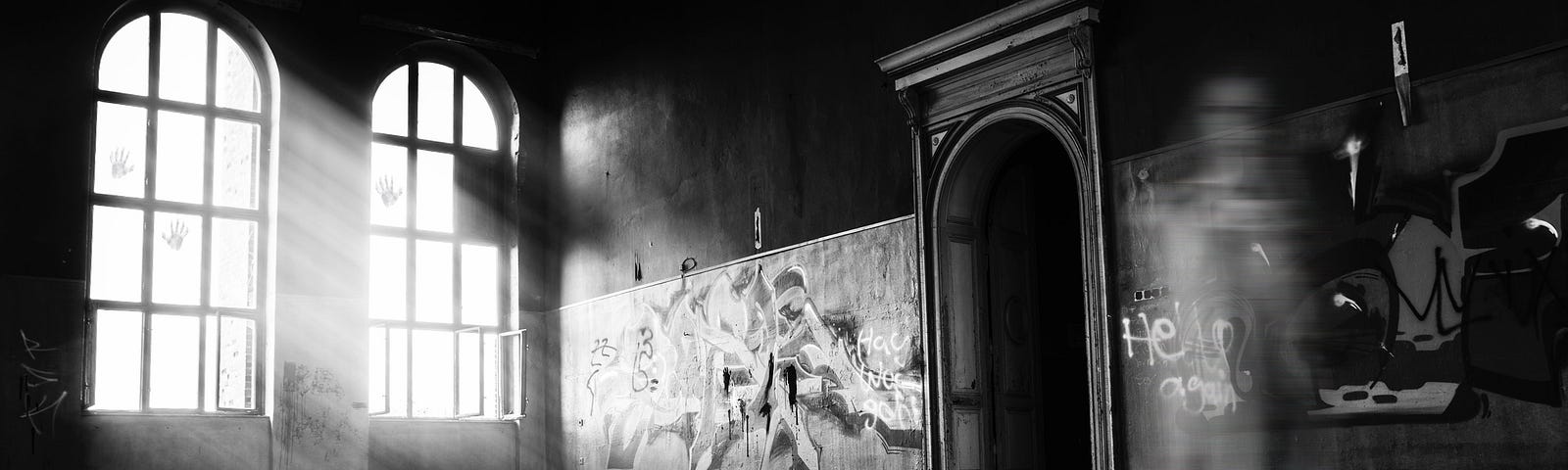 Greyscale photo of an abandoned room with the shadow of a figure standing off-centre