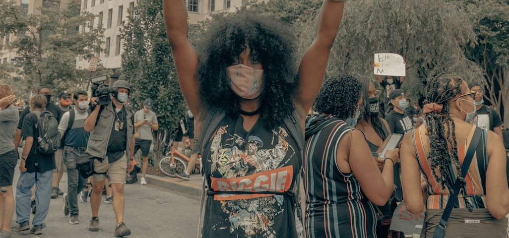 A woman with a Covid mask protests on the street.