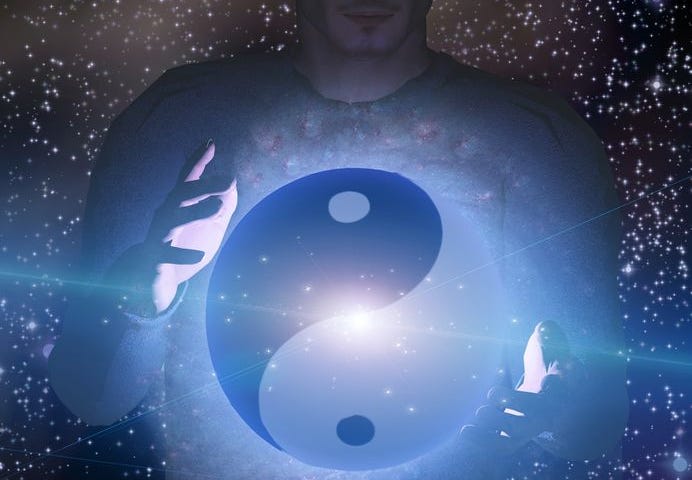 A yin-yang symbol floating as a ball between someone’s hands against a starfield.