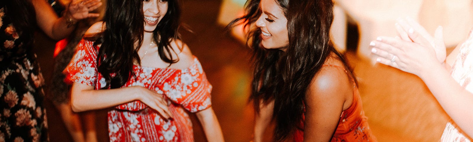 Two latinas smile while dancing How to Learn to Cumbia by Jim Latham | Photo by Omar Lopez on Unsplash