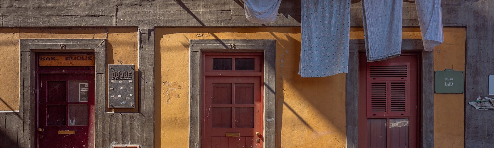 A blonde girl in pink walks up set of stairs with laundry hanging over her head. At First Sight by Jim Latham