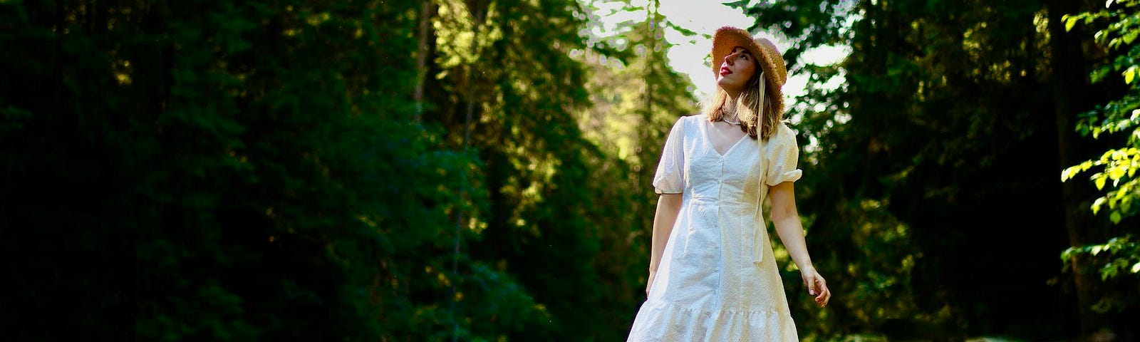 A woman in a white dress with red boots stands in a forest