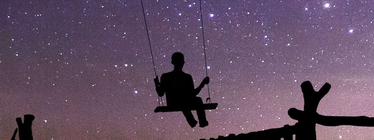 Silhouette of a person in a swing against a starry evening sky