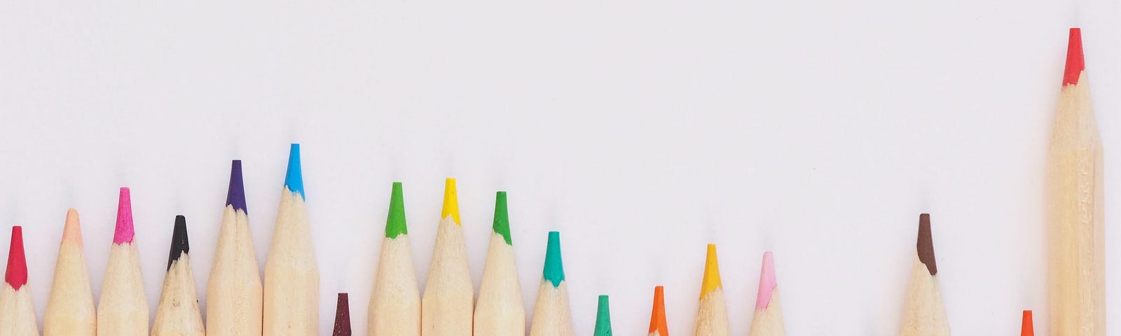 Photo by Jess Bailey on Unsplash showing a line of brightly colored pencils lined up at different heights