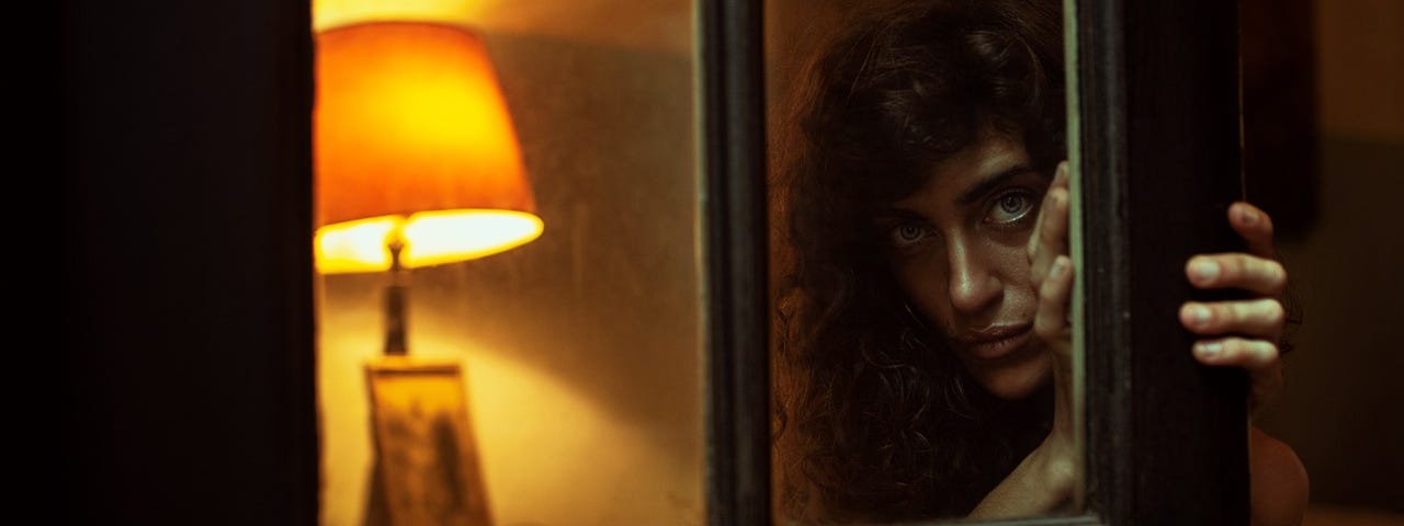 A woman peering through the glass window on the door.