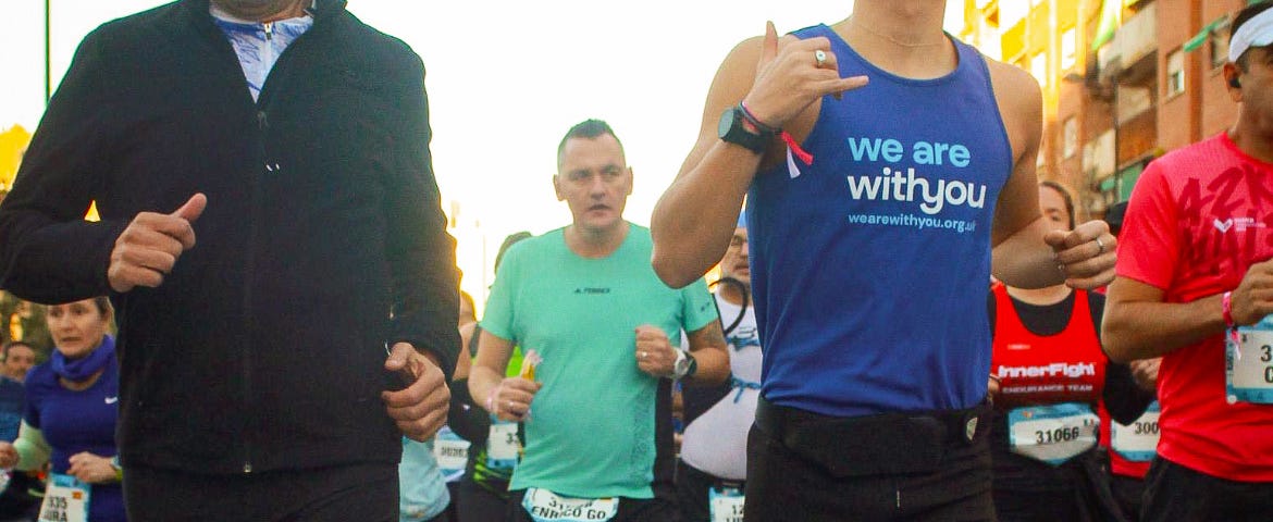 Harry, wearing a WeAreWithYou vest, running in a marathon.