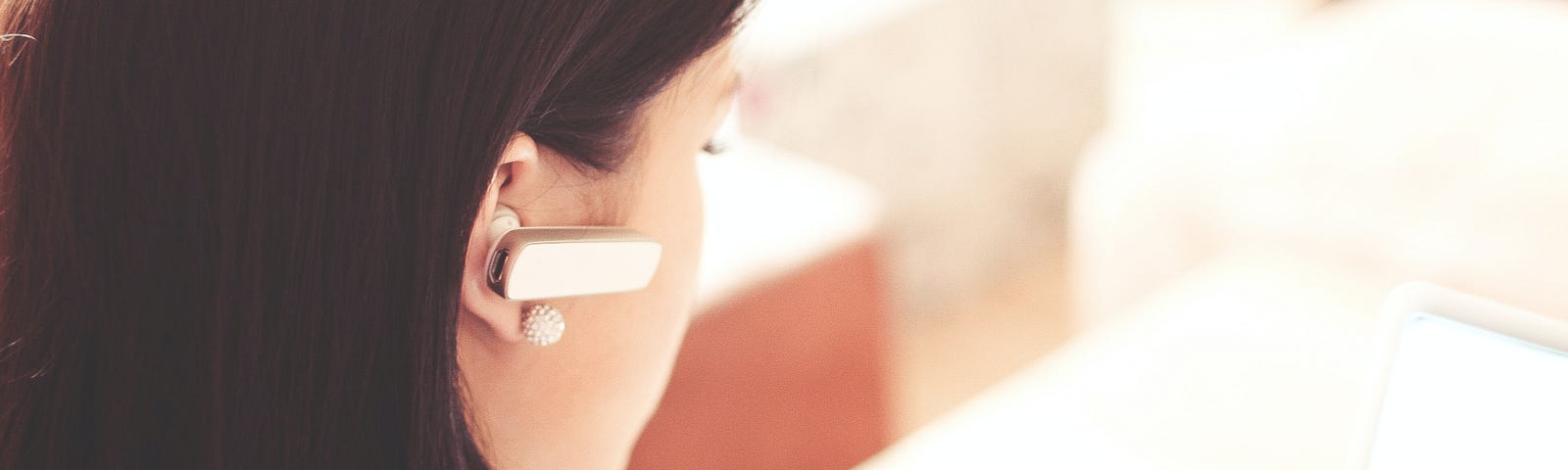 Woman at a laptop wearing a bluetooth earpiece